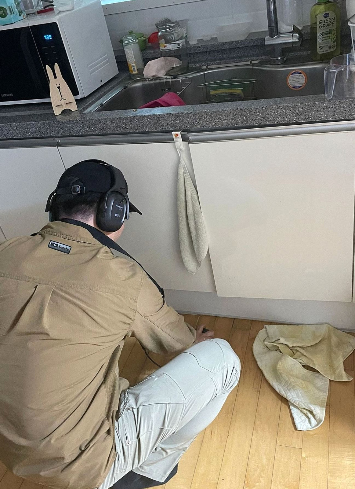 서교동 싱크대 누수 확인을 위해 주방 하부장 앞에서 청음 탐지하는 모습